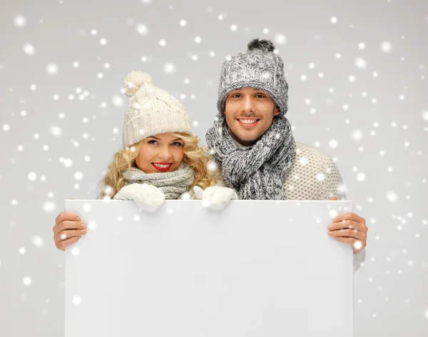 Paar in een winter kleding bedrijf leeg bord — Stockfoto