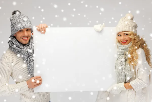 Paar in een winter kleding bedrijf leeg bord — Stockfoto