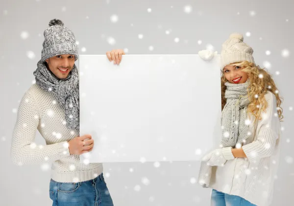 Paar in een winter kleding bedrijf leeg bord — Stockfoto