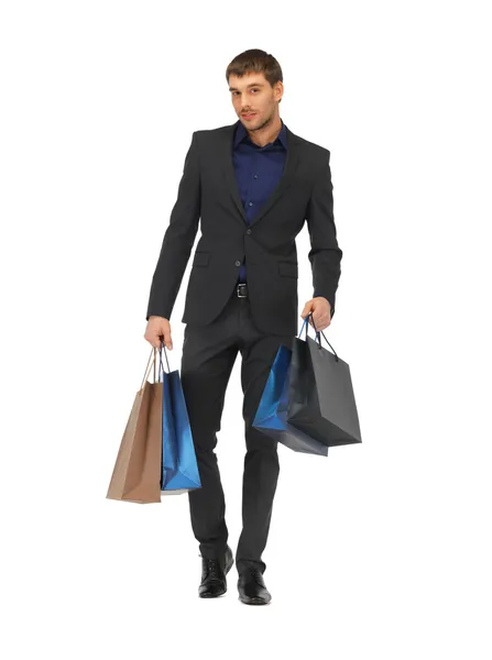 Bello uomo in giacca e cravatta con shopping bags — Foto Stock