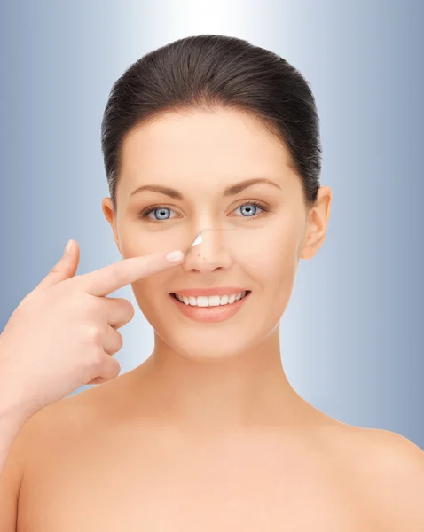 Beautiful woman pointing to nose — Stock Photo, Image