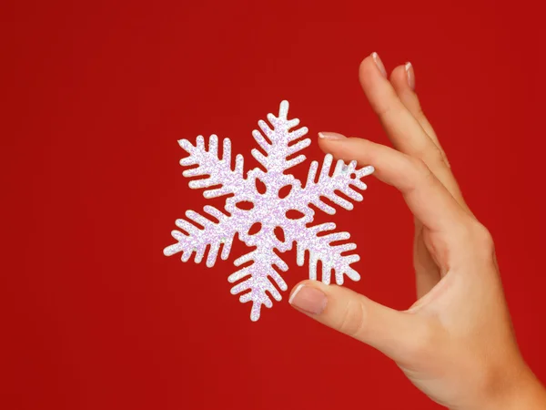 Frauenhände halten eine Schneeflocke — Stockfoto