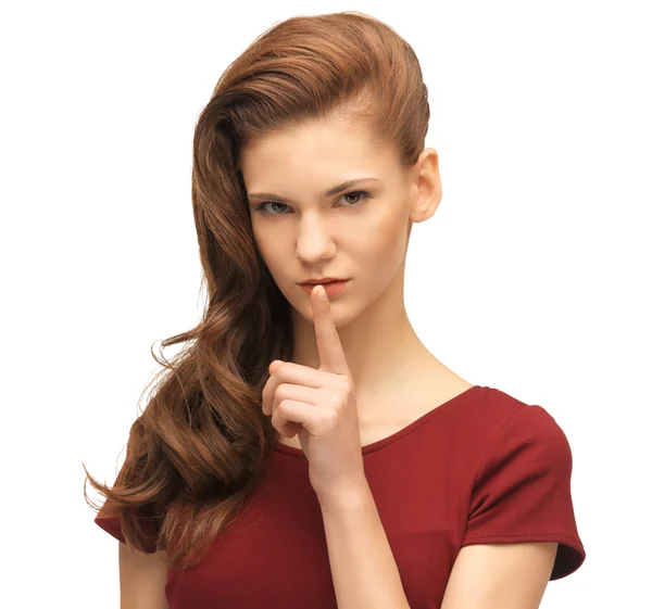 Tiener meisje in een rode jurk met vinger op lippen — Stockfoto