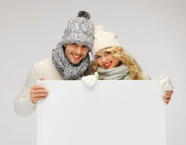 Casal em uma roupa de inverno segurando placa em branco — Fotografia de Stock