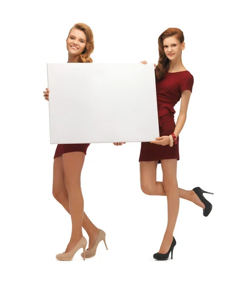 Duas meninas adolescentes em vestidos vermelhos com placa em branco — Fotografia de Stock