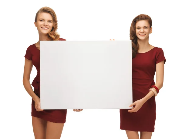 Twee tienermeisjes in rode jurken met leeg bord — Stockfoto