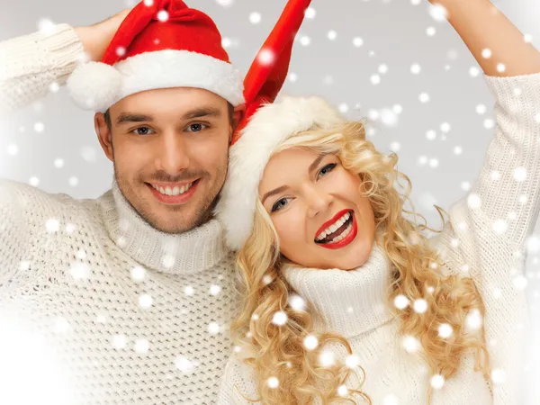 Casal de família em camisolas e chapéus de Papai Noel — Fotografia de Stock