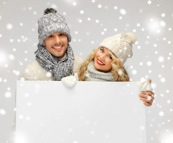 Casal em uma roupa de inverno segurando placa em branco — Fotografia de Stock