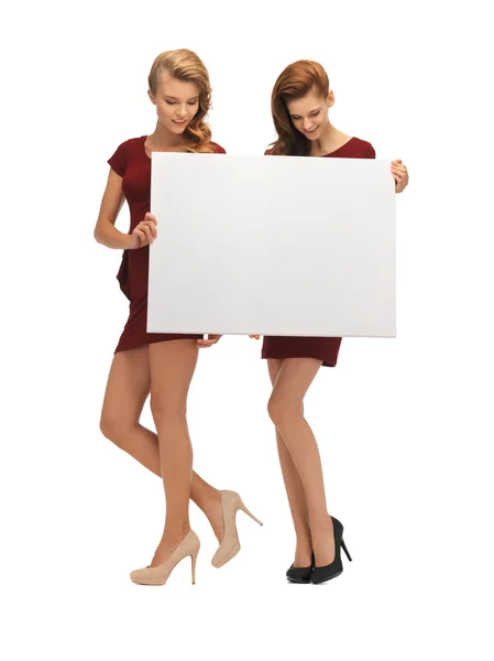 Two teenage girls in red dresses with blank board — Stock Photo, Image