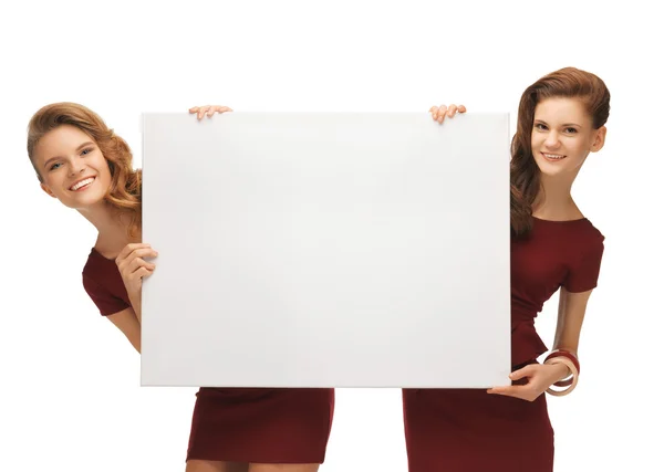 Two teenage girls in red dresses with blank board — Stock Photo, Image