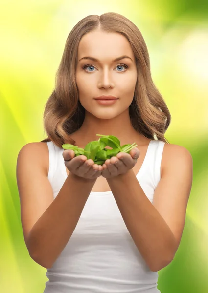 Woman with spinach leaves on palms — Stock Photo, Image