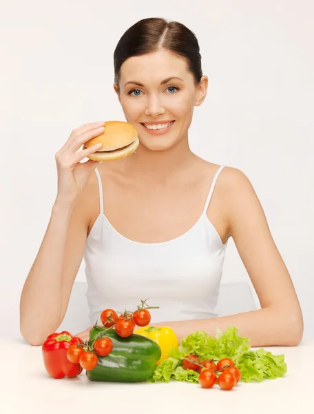Kvinna med hamburgare och grönsaker — Stockfoto