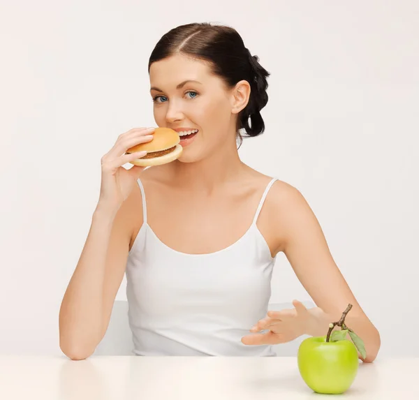 Woman with hamburger and vegetables Royalty Free Stock Images