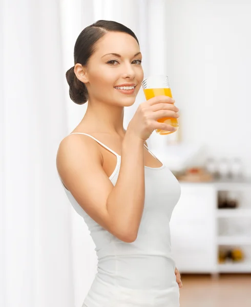 Mulher com copo de suco na cozinha — Fotografia de Stock