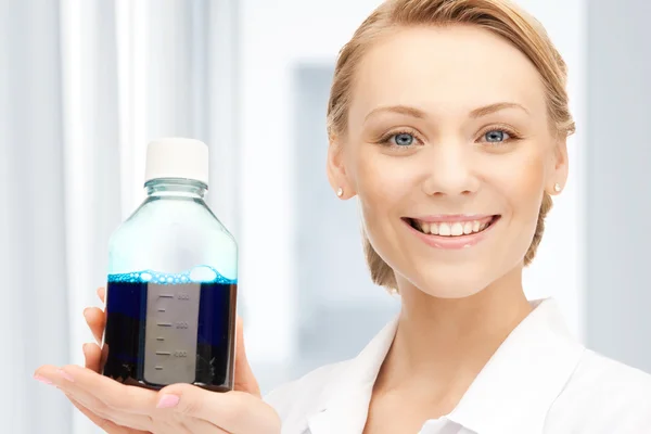 Lab worker holding up bottle with blue liquid — Stock Photo, Image