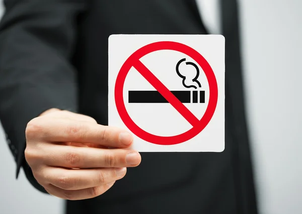 Man in suit holding no smoking sign — Stockfoto