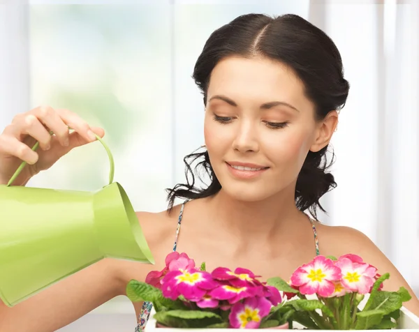 Huisvrouw met bloem in pot en gieter — Stockfoto