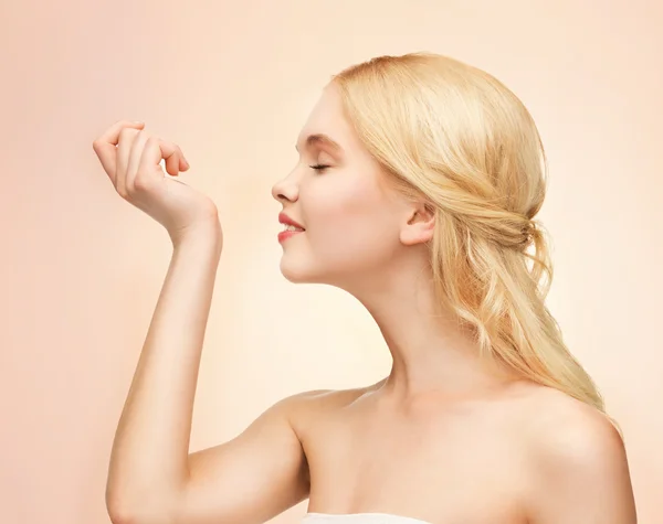 Young girl smelling pefrume on her hand — Stock Photo, Image