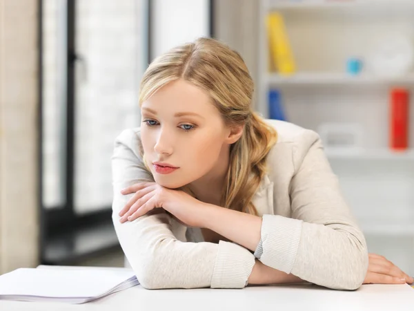 Mujer aburrida y cansada detrás de la mesa — Foto de Stock