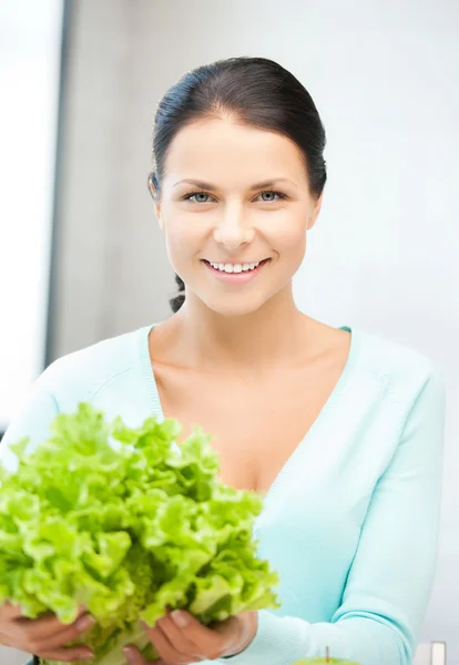 Kvinnan i köket med grönsallad lämnar — Stockfoto