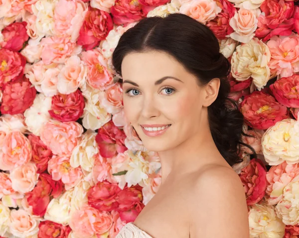 Frau mit Hintergrund voller Rosen — Stockfoto