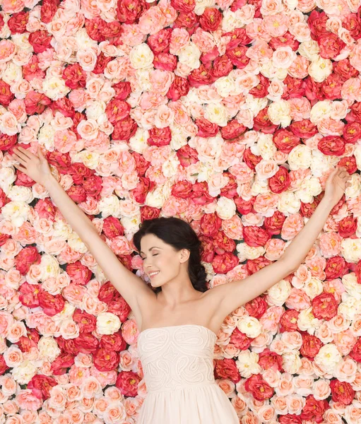 Mujer joven con fondo lleno de rosas — Foto de Stock