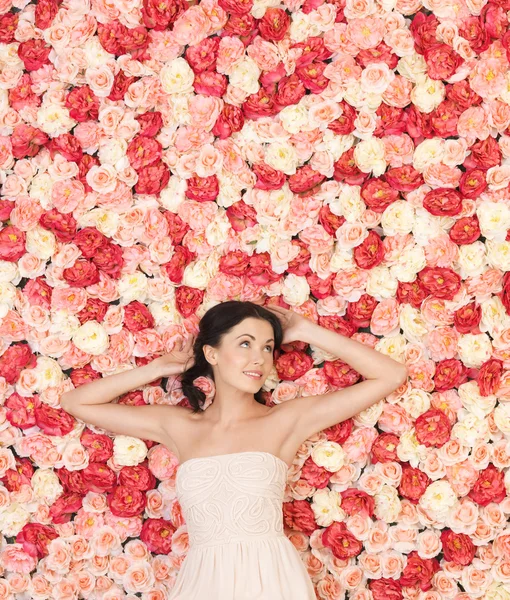 Junge Frau mit Hintergrund voller Rosen — Stockfoto