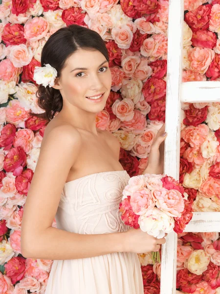 Vrouw met boeket en achtergrond vol rozen — Stockfoto