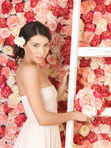 Frau mit Strauß und Hintergrund voller Rosen — Stockfoto