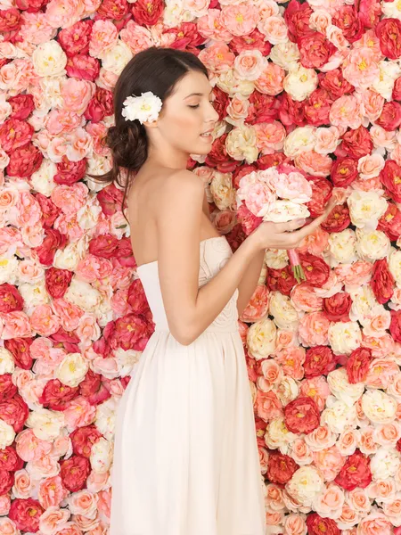 Mulher com buquê e fundo cheio de rosas — Fotografia de Stock