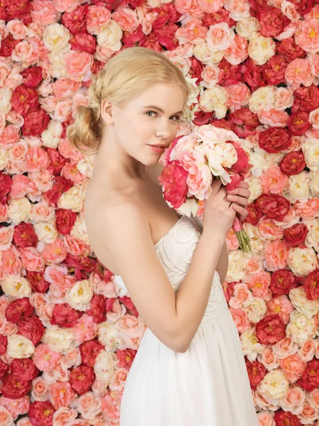 Frau mit Strauß und Hintergrund voller Rosen — Stockfoto