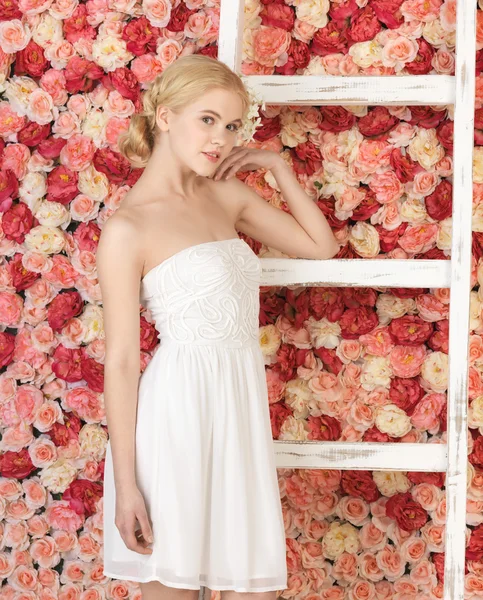 Vrouw met oude ladder en achtergrond vol rozen — Stockfoto