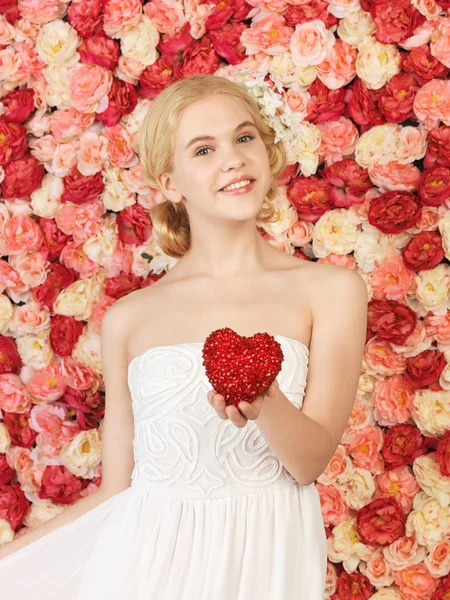 Mulher com coração e fundo cheio de rosas — Fotografia de Stock