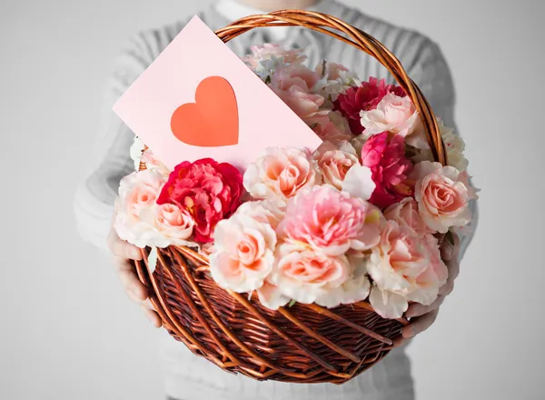 Man holding basket full of flowers and postcard — Stock Photo, Image