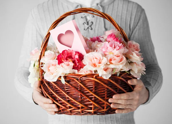 Hombre sosteniendo cesta llena de flores y postal — Foto de Stock