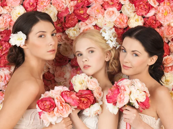Tre kvinnor med bakgrund som är full av rosor — Stockfoto