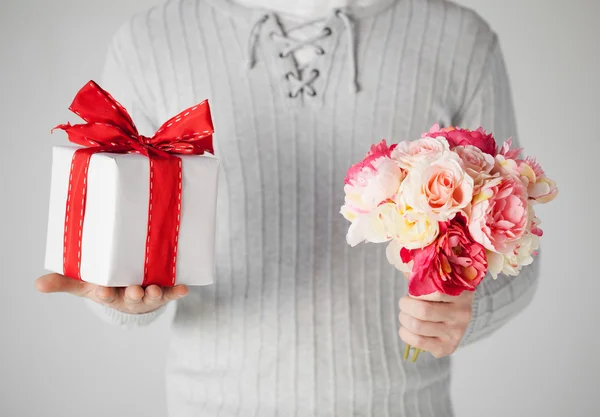 Мужчина с букетом цветов и подарочной коробкой — стоковое фото
