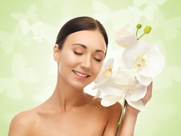 Donna sorridente con fiore bianco di orchidea — Foto Stock