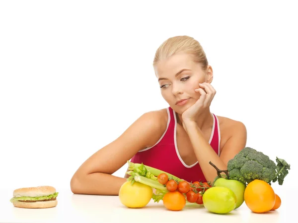 Mulher duvidando com frutas e hambúrguer — Fotografia de Stock