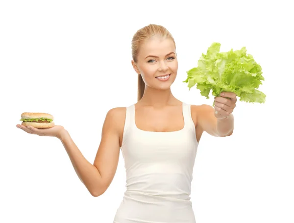 Woman with green leaves and hamburger — Stock Photo, Image