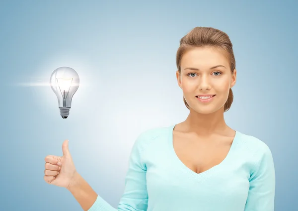 Woman with light bulb showing thumbs up Stock Picture