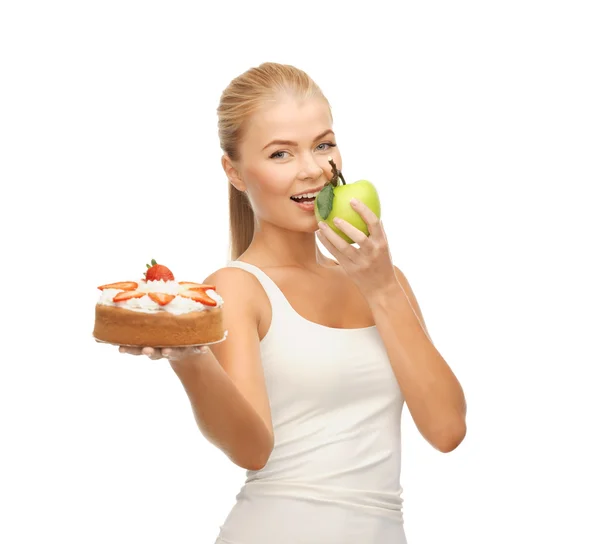 Жінка їсть яблуко і тримає торт Ліцензійні Стокові Фото