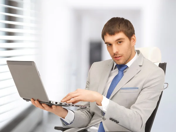 Joven hombre de negocios sentado en silla con portátil —  Fotos de Stock