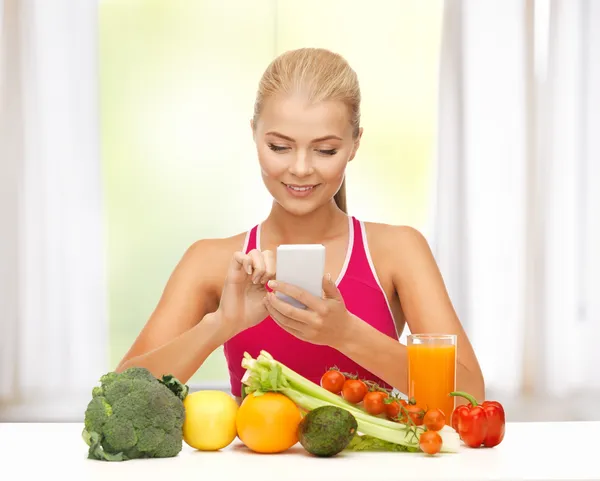 Kvinna med frukt, grönsaker och smartphone — Stockfoto