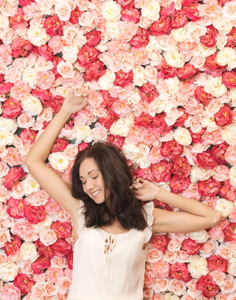 Vacker kvinna och bakgrund full av rosor — Stockfoto