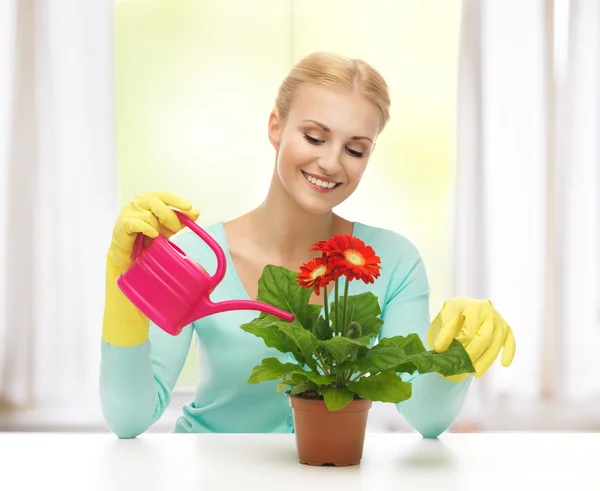 Домохозяйка с цветами в горшочке и лейкой — стоковое фото