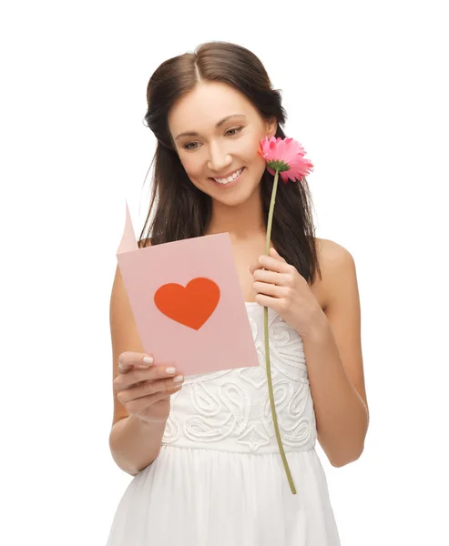 Mladá žena drží květinu a pohlednice — Stock fotografie