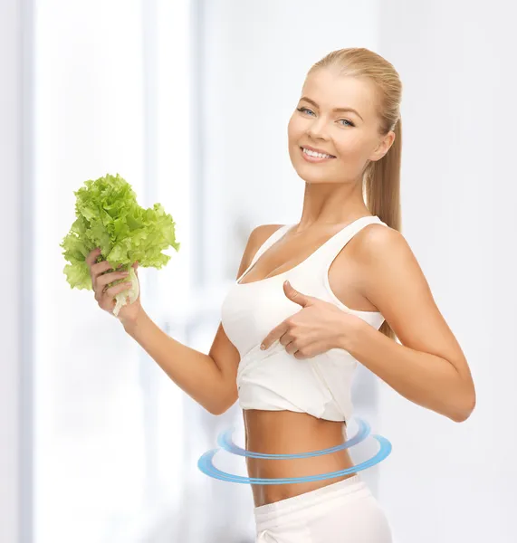 Sportiga kvinnan med sallad visar abs — Stockfoto