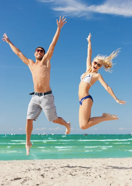 Casal pulando na praia — Fotografia de Stock