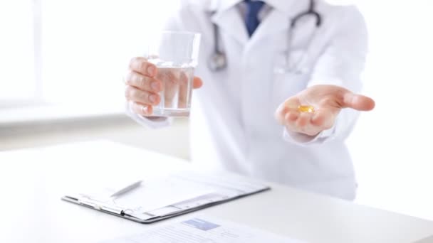 Крупный план рук врача-мужчины с таблетками и стаканом воды — стоковое видео